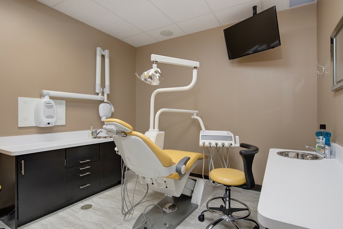 a dental office with a yellow dentist chair in the middle of the room
