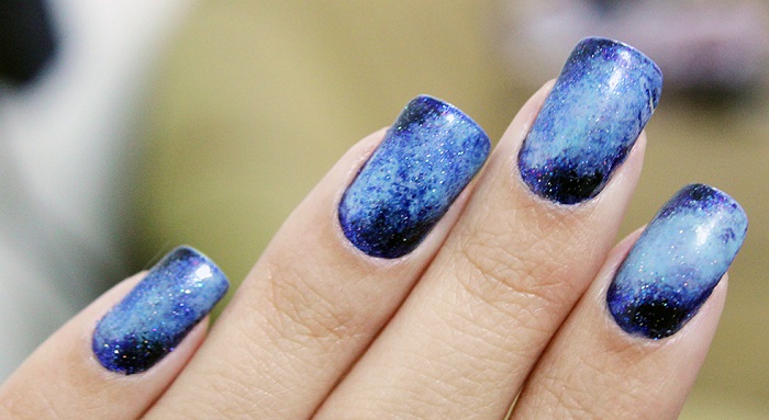 a woman's nails with a galaxy pattern manicure