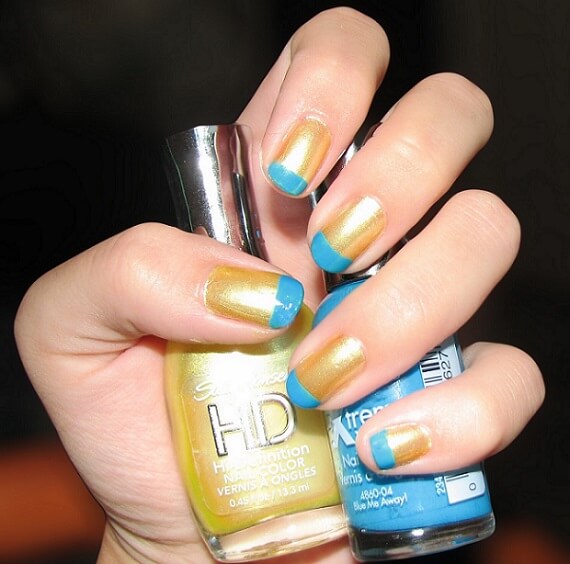 a modern french manicure with gold nail polish and blue tips 
