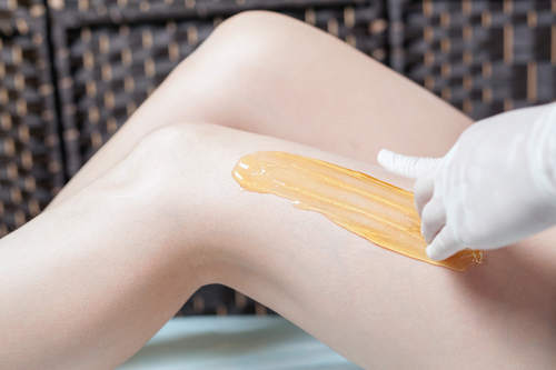 a woman's legs and a beautician applying a sugar hair removal procedure