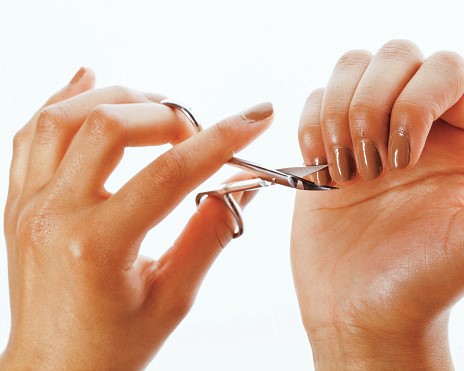 a woman's hands with short polished nails, holding a pair of scissors