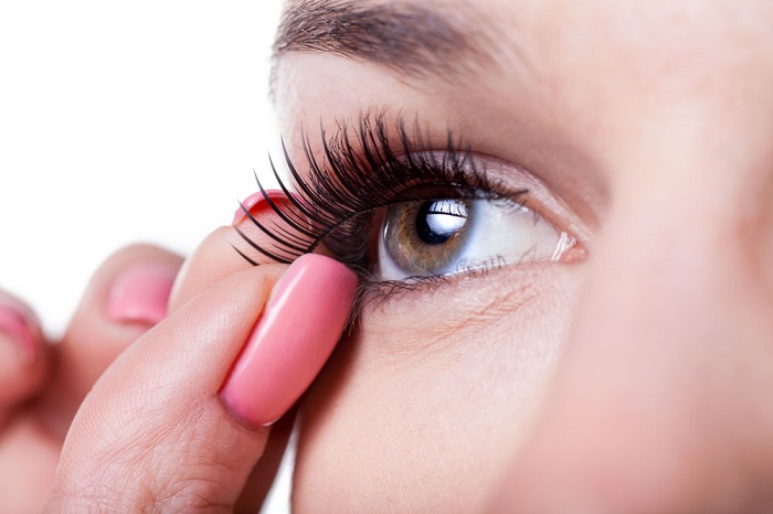a woman trying to remove her fake eyelashes