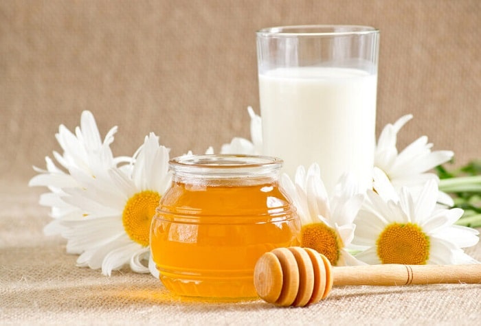 a jar or honey and a glass of milk