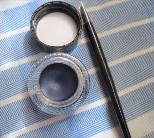 A pot with black gel eyeliner, with the cap and the brush next to it