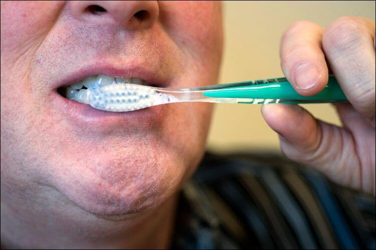 Close up of a man's mouth while he is brushing his teeth