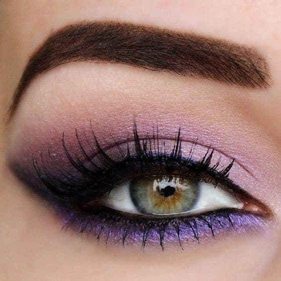closeup on green eye and eyebrow with purple makeup on